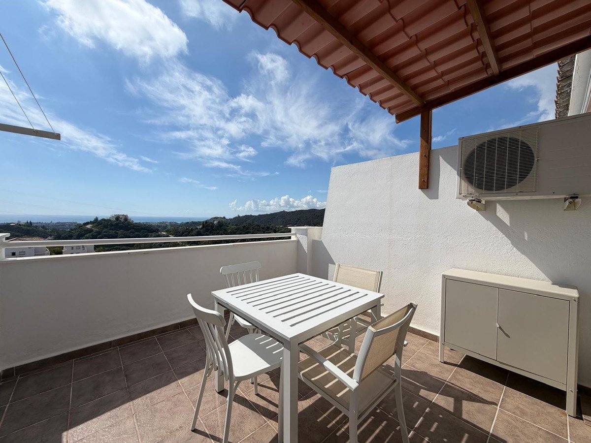 Balcony with white table and chairs overlooking a scenic landscape