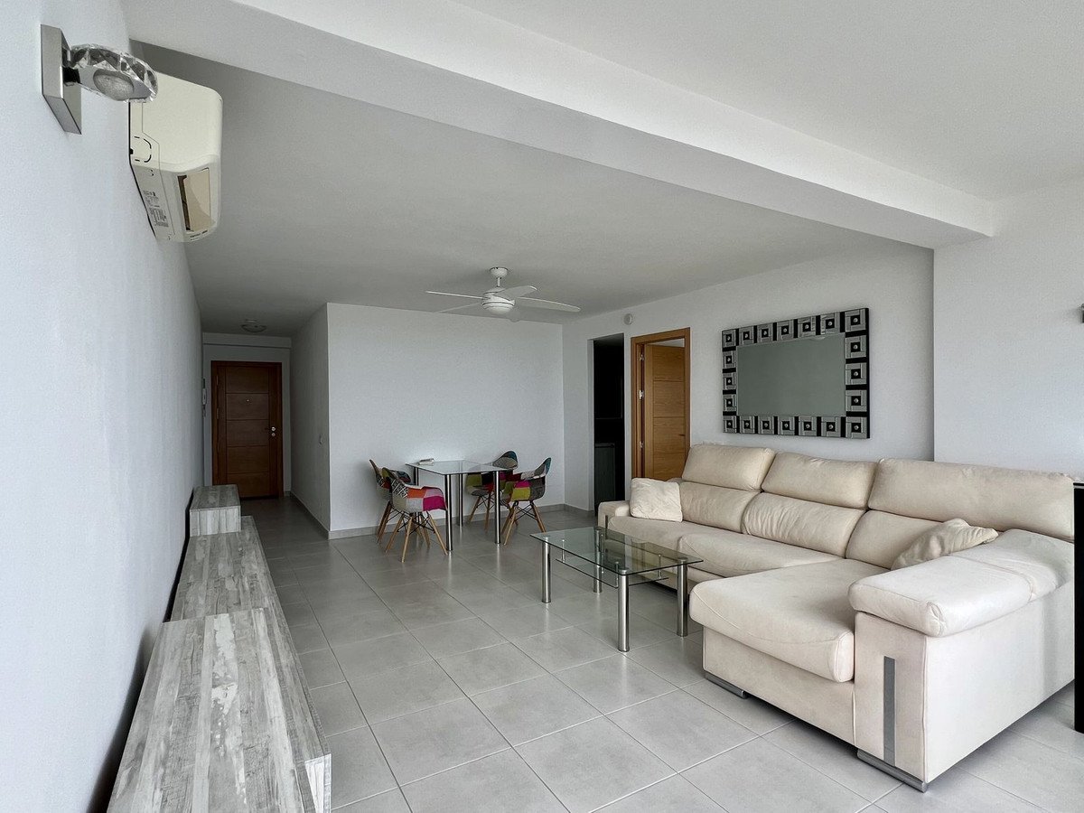 Living room with beige sofa, glass coffee table, and modern wall art