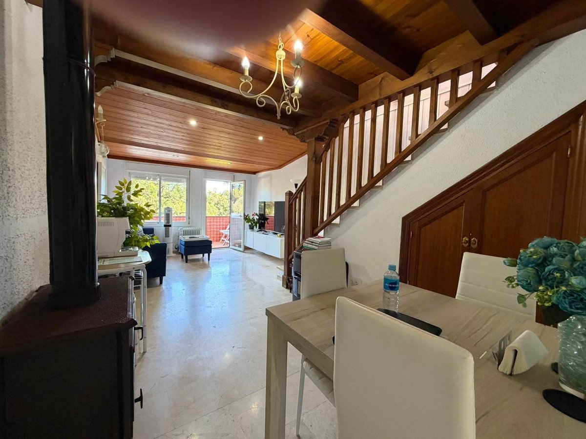 Spacious living room with dining table, staircase, and large windows
