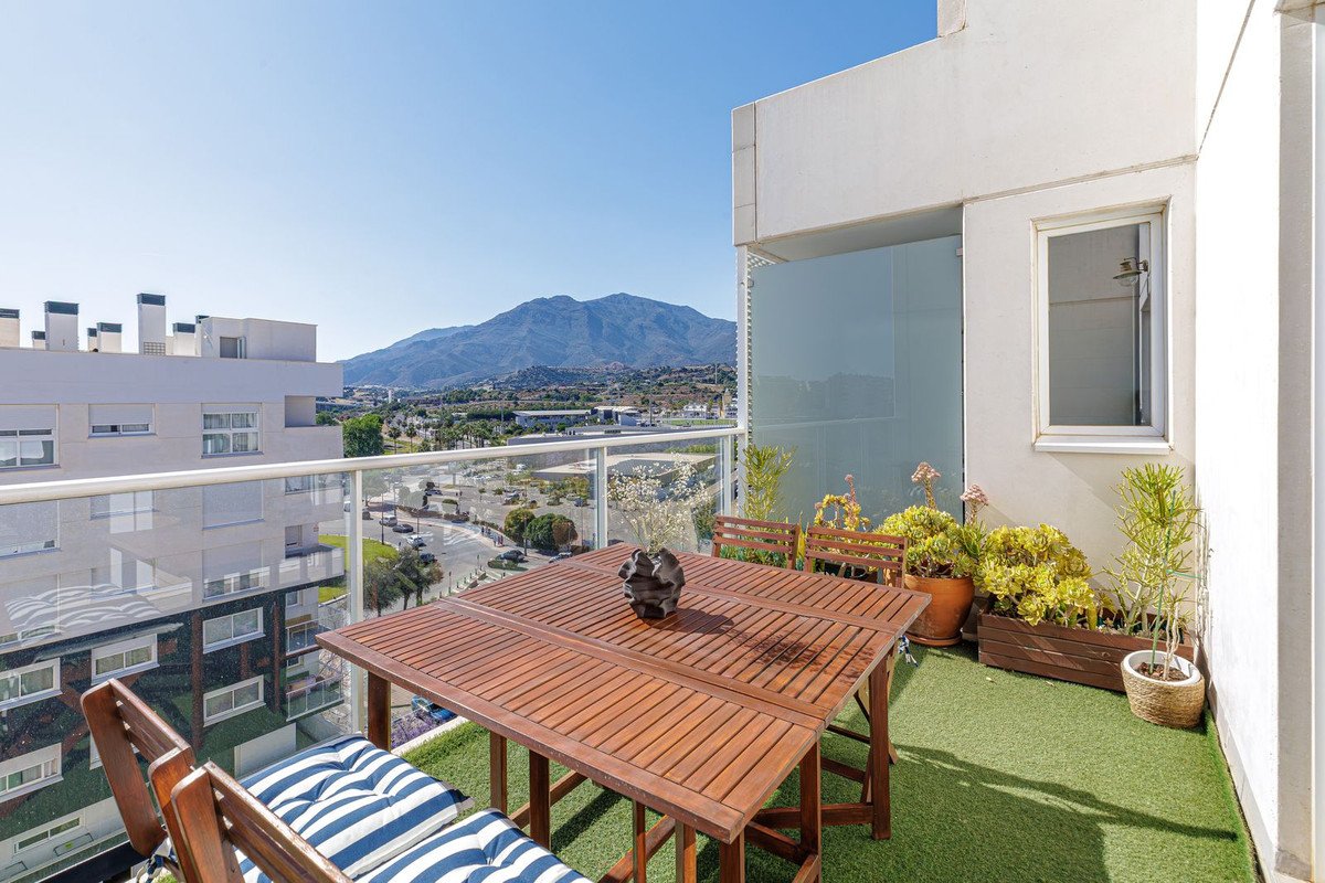 Balcony with wooden table and chairs overlooking mountains