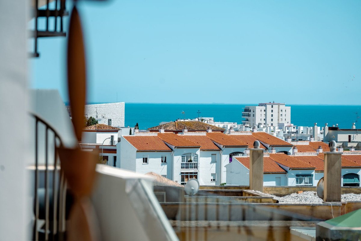 Balcony view of white-roofed houses and the sea in the distance