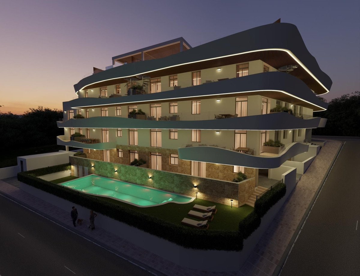 Modern apartment building with curved balconies, pool, and evening lighting.