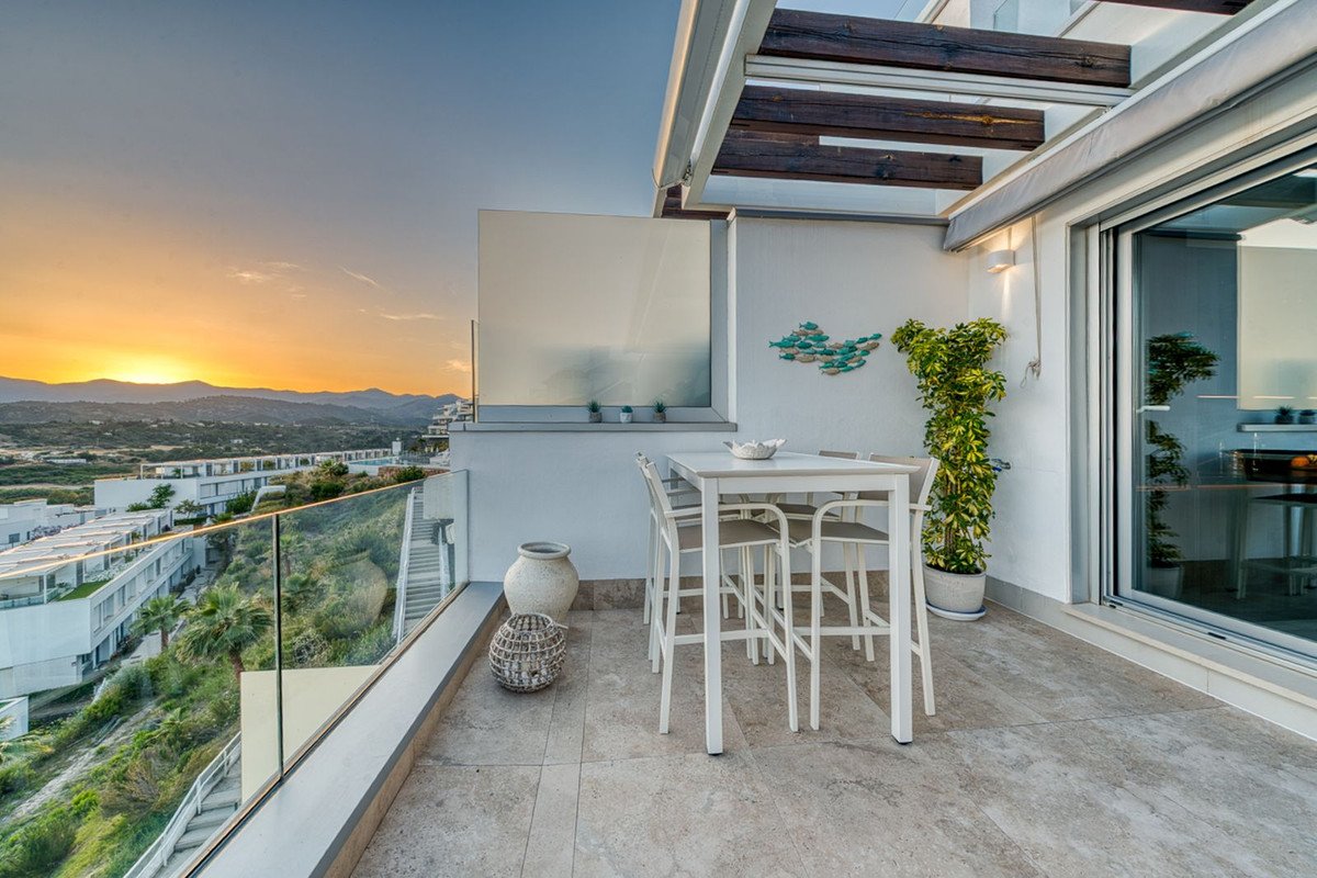 Modern terrace with dining table, sunset view, and glass railing