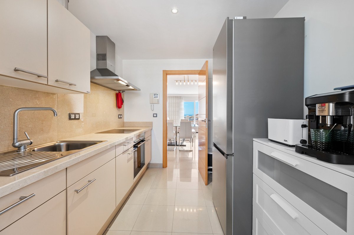 Modern kitchen with white cabinets, stainless steel appliances, and a view into a dining area.