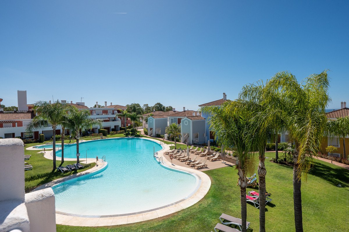 Villa with pool view, palm trees, and lounge chairs under clear blue sky.