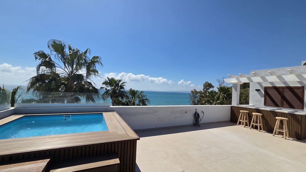 Infinity pool overlooking the ocean with a bar area and palm trees