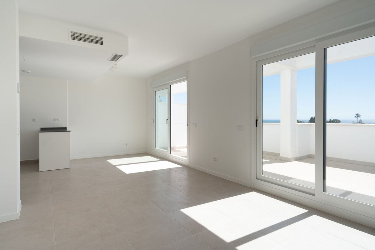 Modern spacious living room with large sliding glass doors opening onto a balcony with a sea view.
