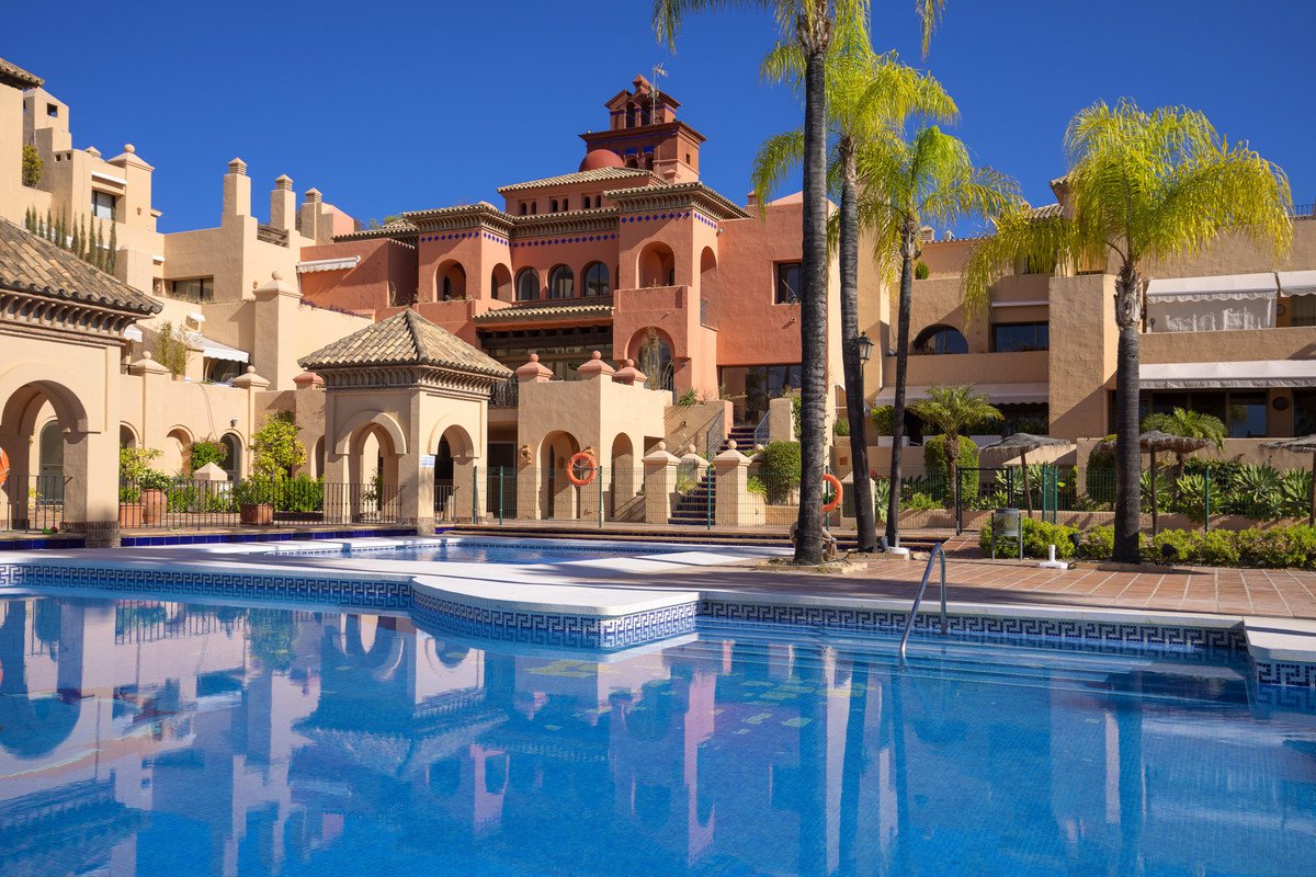 Luxurious swimming pool with Mediterranean-style building and palm trees