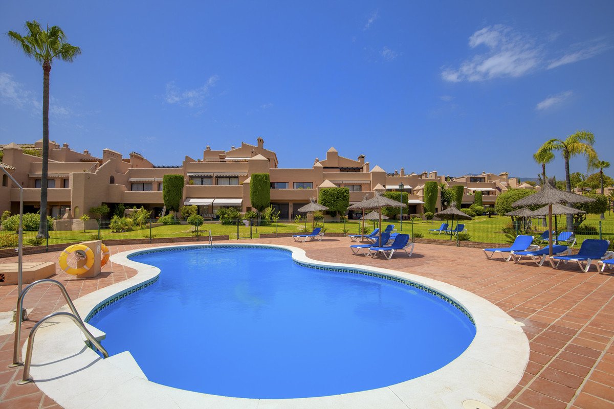 Luxurious swimming pool with lounge chairs and resort-style buildings in the background