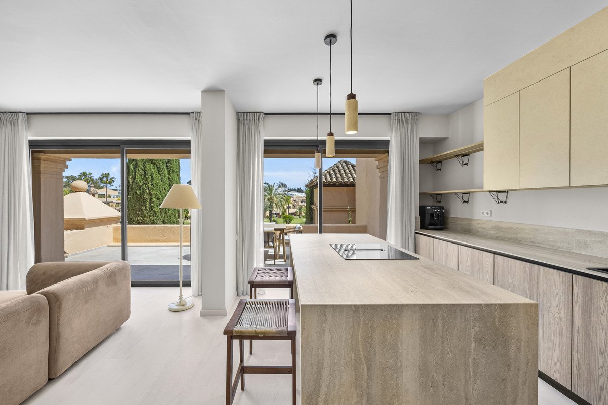 Modern living room with kitchen view featuring large windows and outdoor scenery