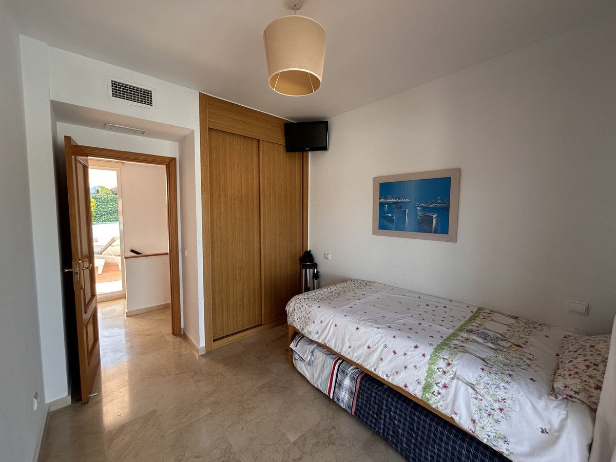 A bedroom with a single bed, built-in wardrobe, and access to a terrace with outdoor seating.