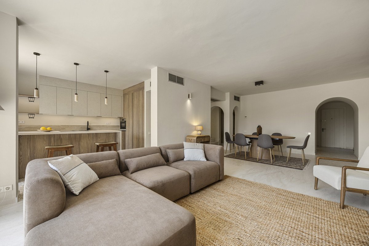Modern living room with beige sofa, kitchen area, and dining table