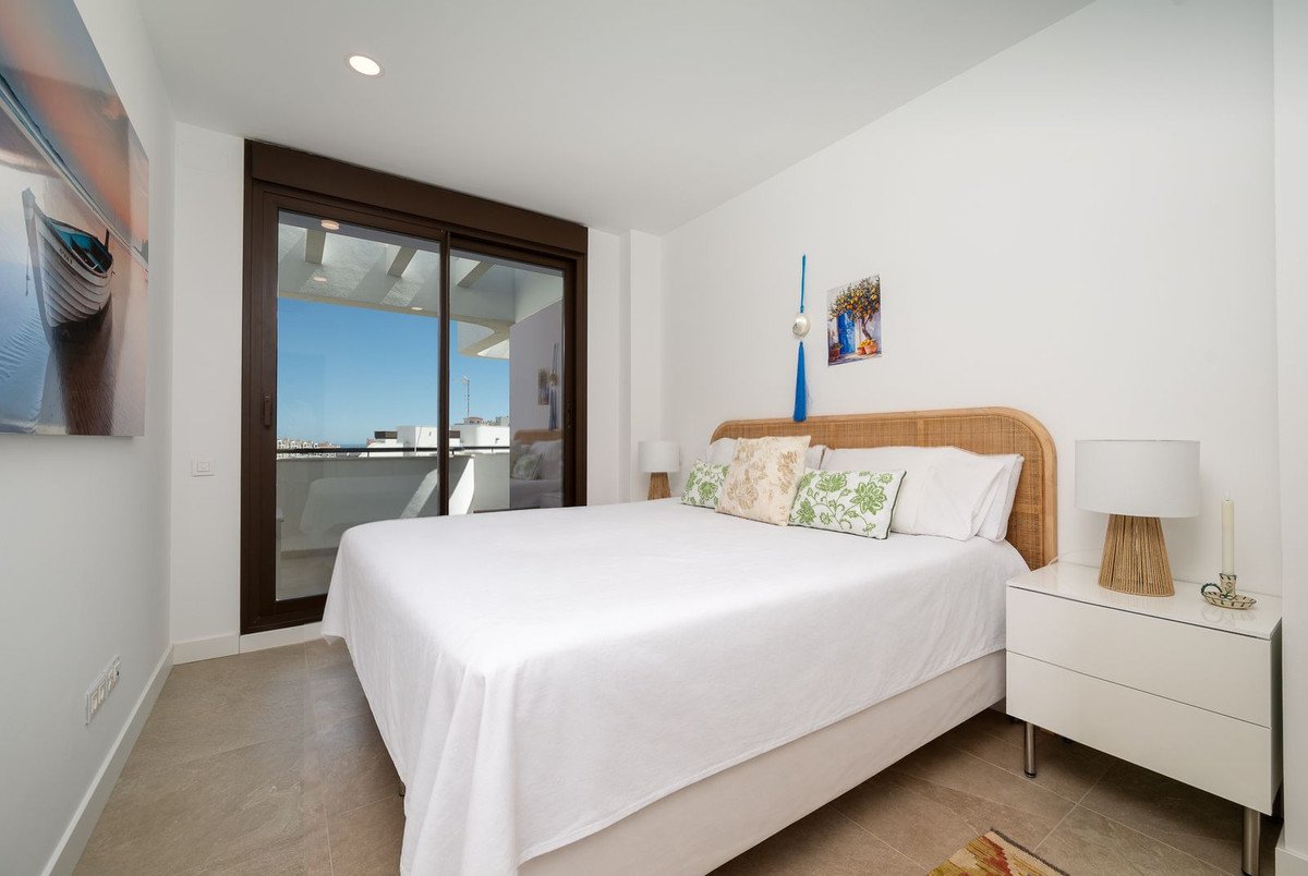 Modern bedroom with a king-size bed, featuring a balcony with sea view and contemporary decor.