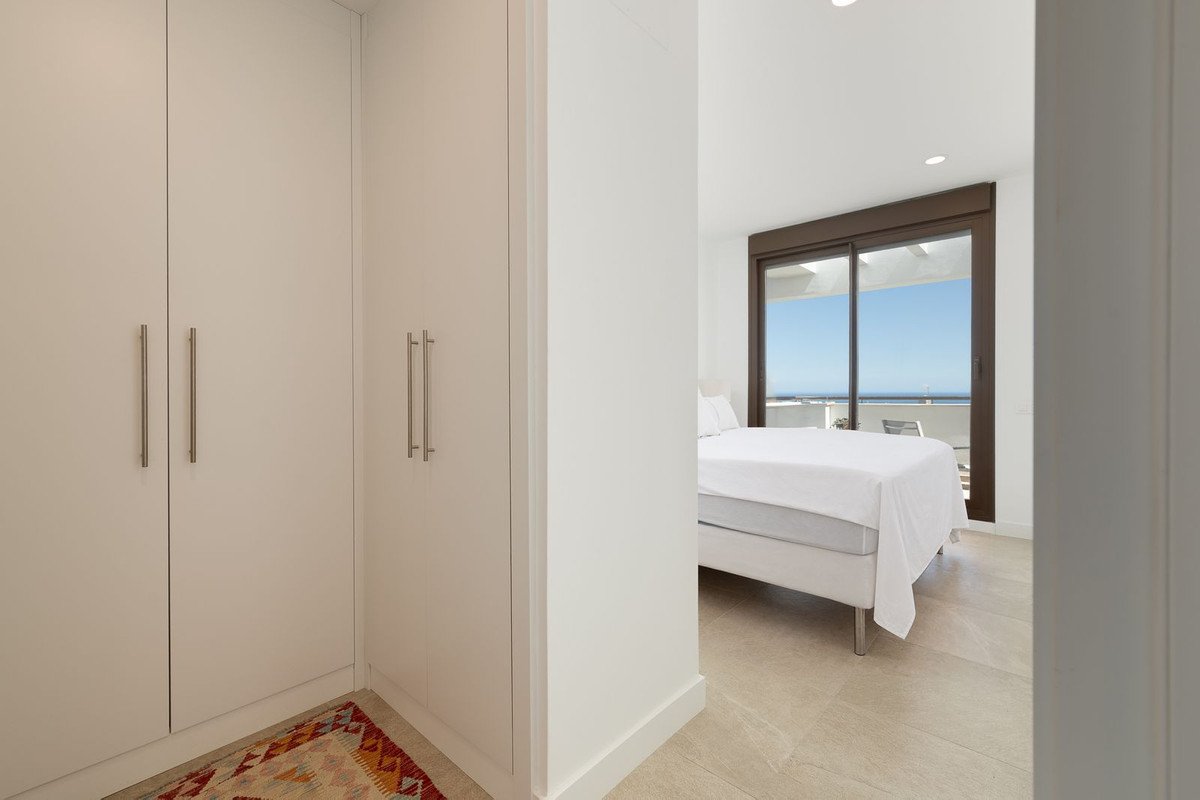 Bedroom with a large bed, sliding glass doors leading to a balcony with an ocean view, and a built-in closet.