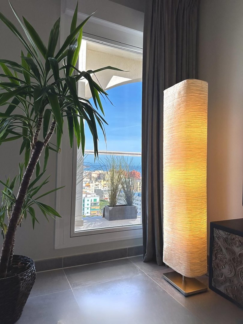 Modern living room with large window overlooking the sea and cityscape