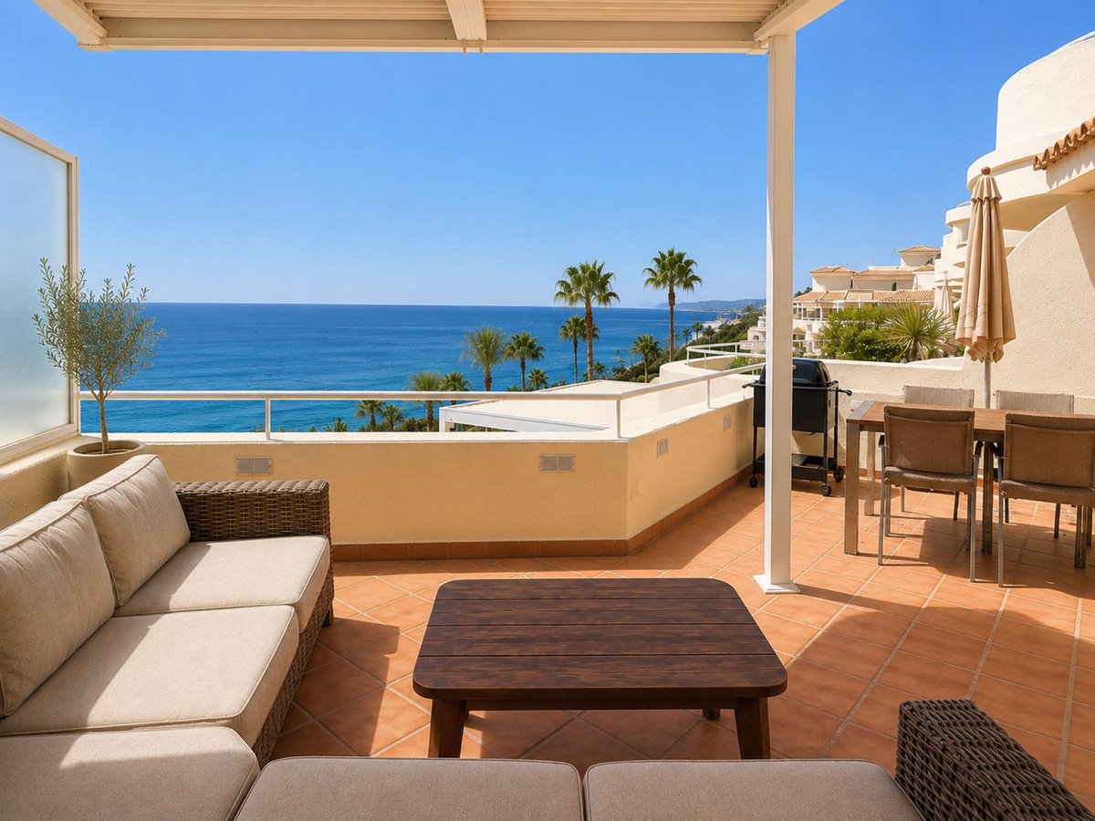 Spacious terrace with a sea view, featuring a dining set, grill, and comfortable sofa with a coffee table.