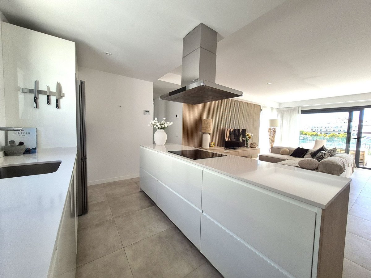 Modern kitchen island with induction hob, opens to a living area with sofa and balcony view.
