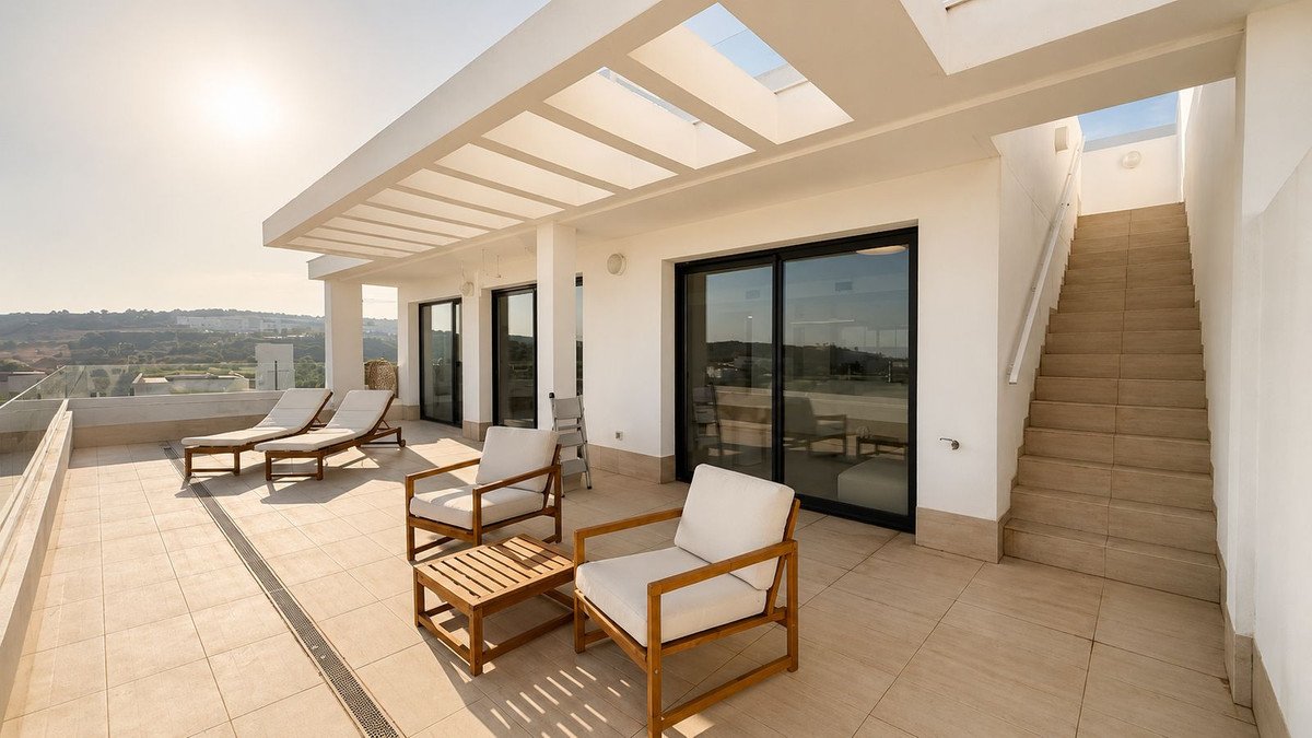 Spacious modern terrace with lounge chairs, coffee table, and stairs leading up. Offers scenic distant views.