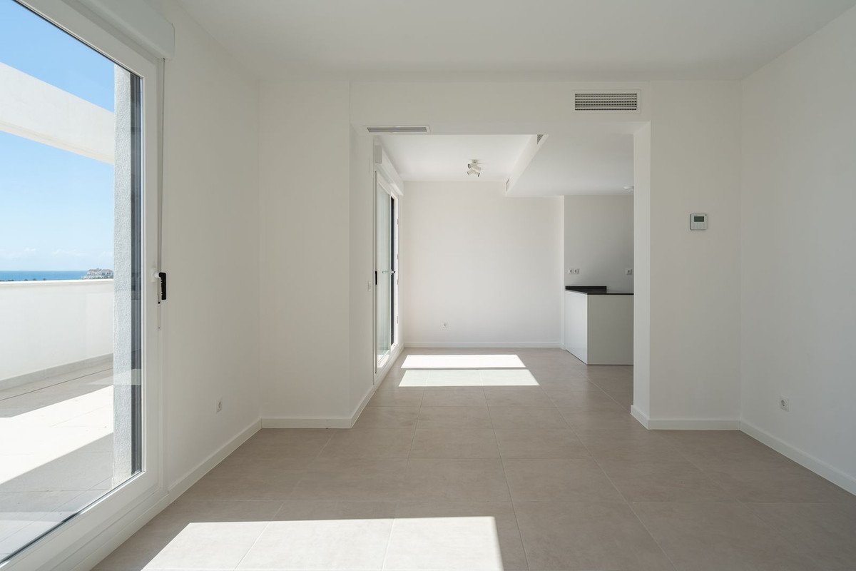 Bright, modern living area with large sliding doors leading to a balcony with a sea view. Air conditioning unit visible.