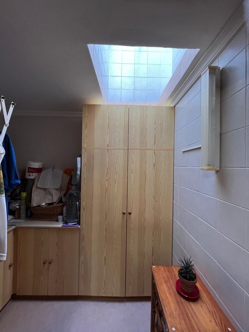 Small room with wooden closet, tile ceiling, and a small desk with a potted plant