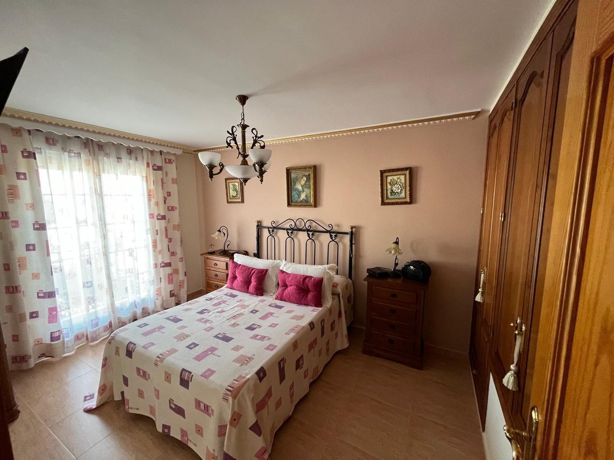 Cozy bedroom featuring a bed with patterned bedding and pink pillows, flanked by wooden nightstands and a wardrobe