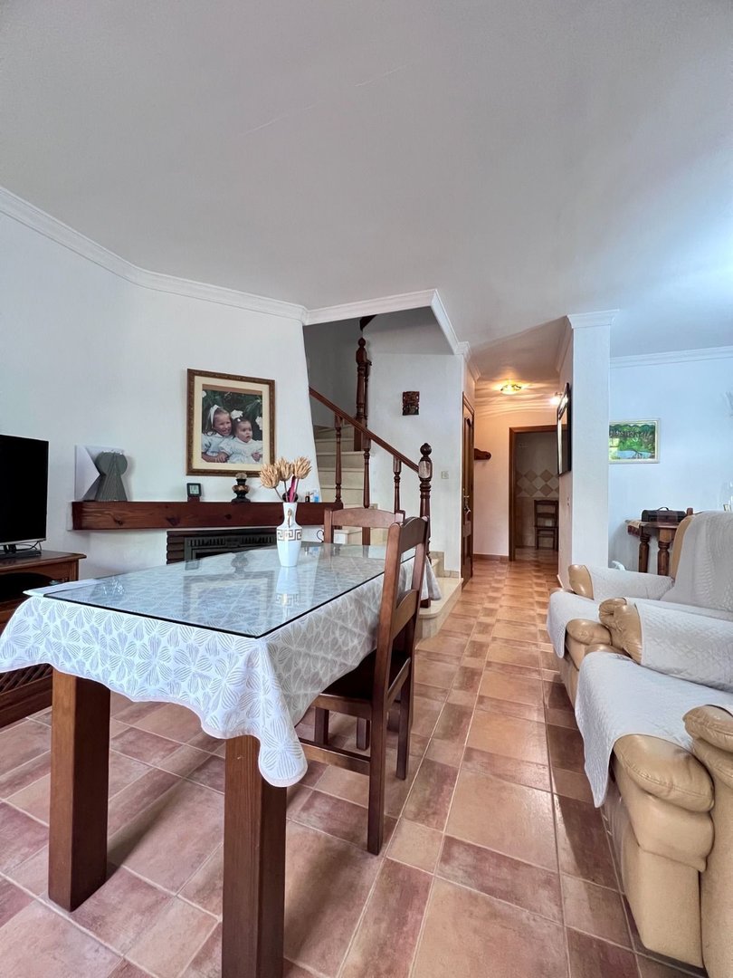 Living room with dining table, sofa, and staircase leading upstairs