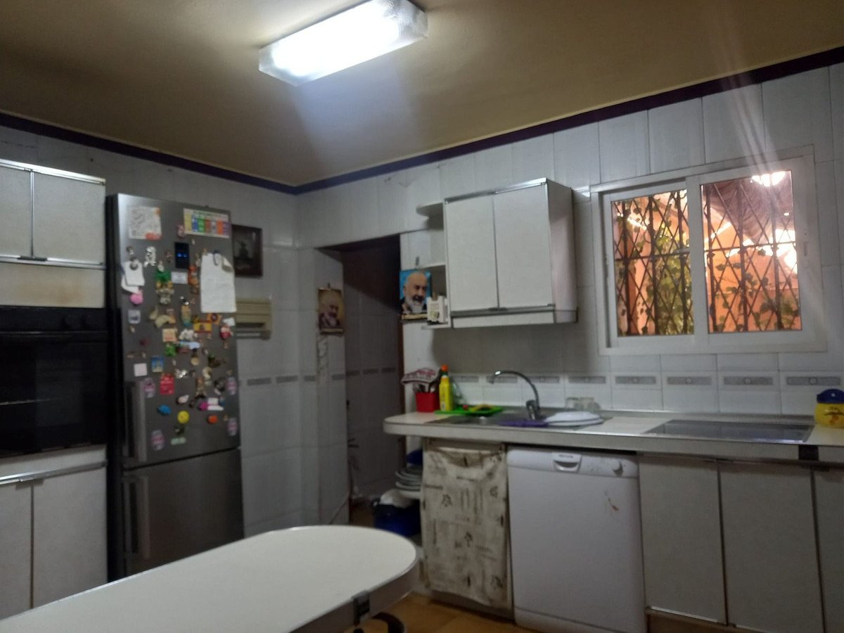 A spacious kitchen featuring a refrigerator, sink, dishwasher, oven, and a window with an outdoor view.