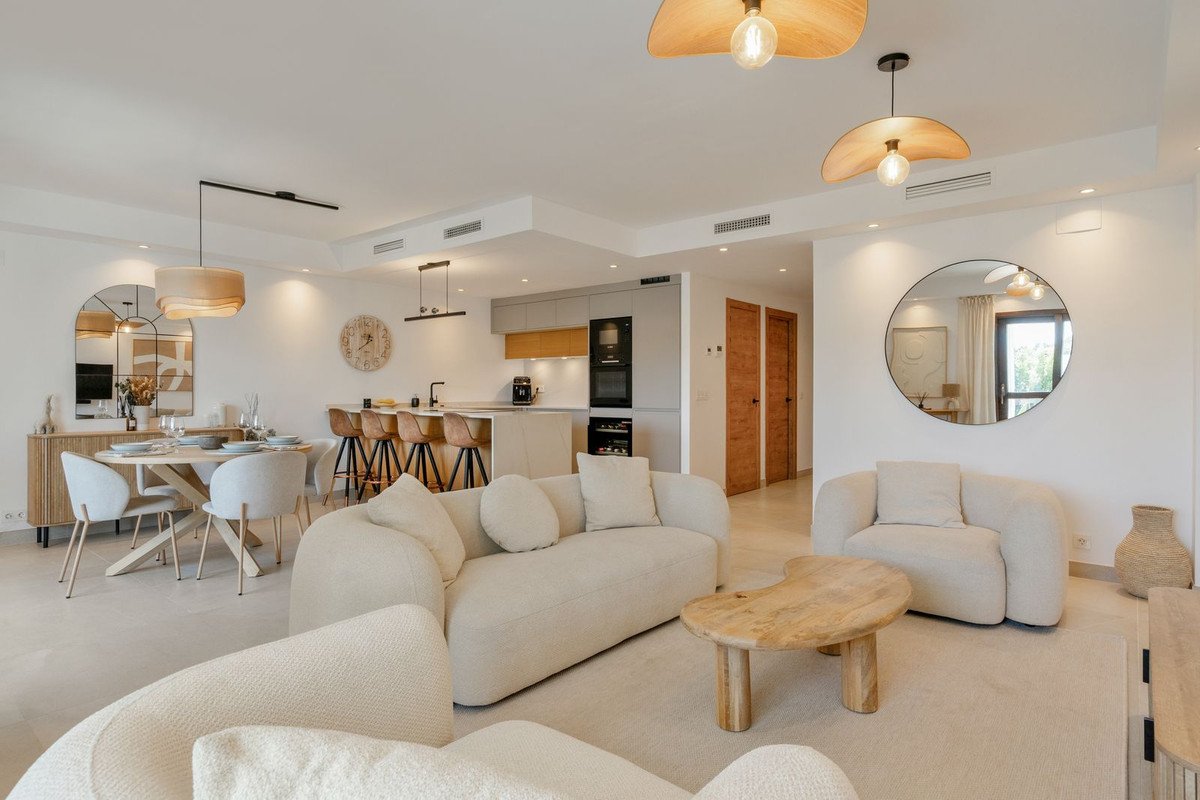 Modern open-plan living room with beige sofa, wooden coffee table, and kitchen in background.