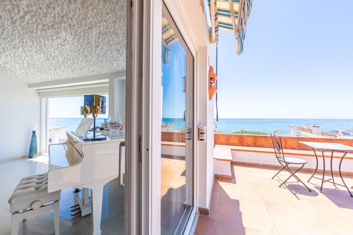 Sunlit room with white piano and ocean view terrace