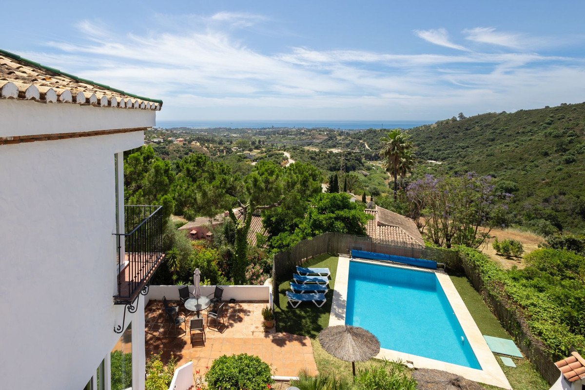 Balcony overlooking a pool and scenic sea view with lush greenery