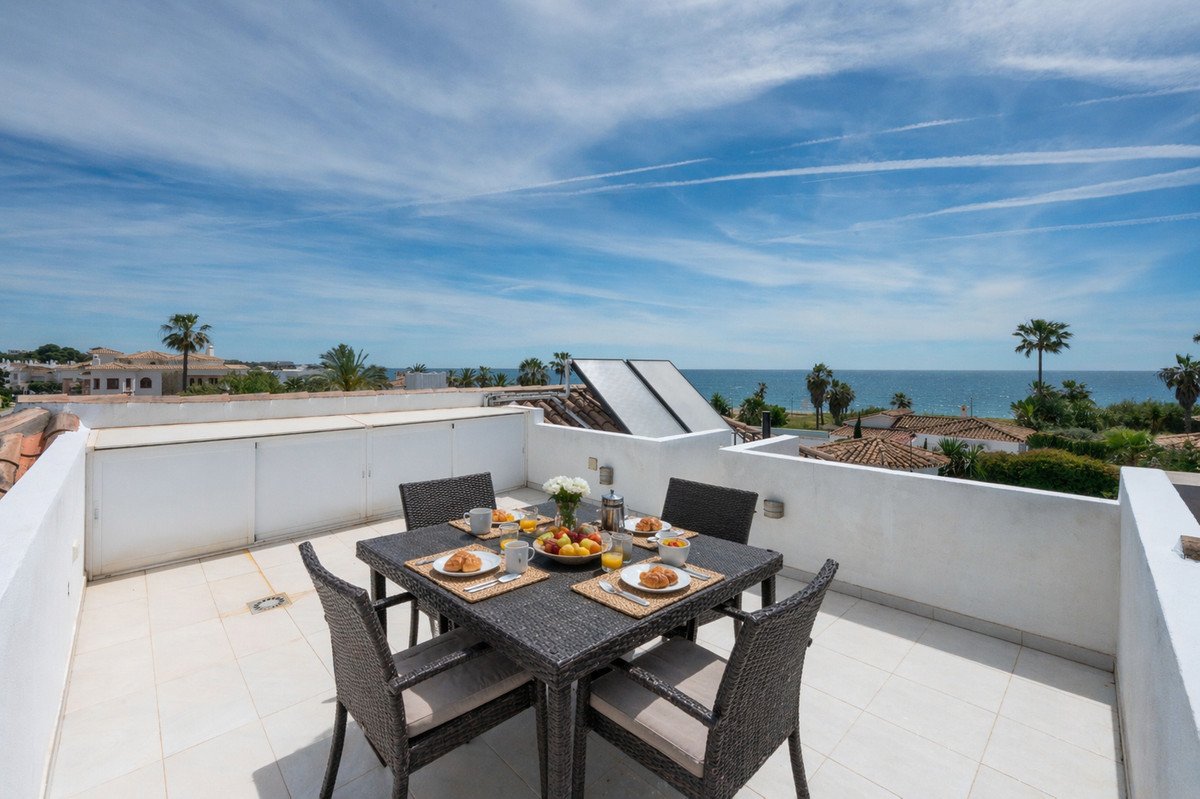 Balcony with breakfast table overlooking the sea and palm trees