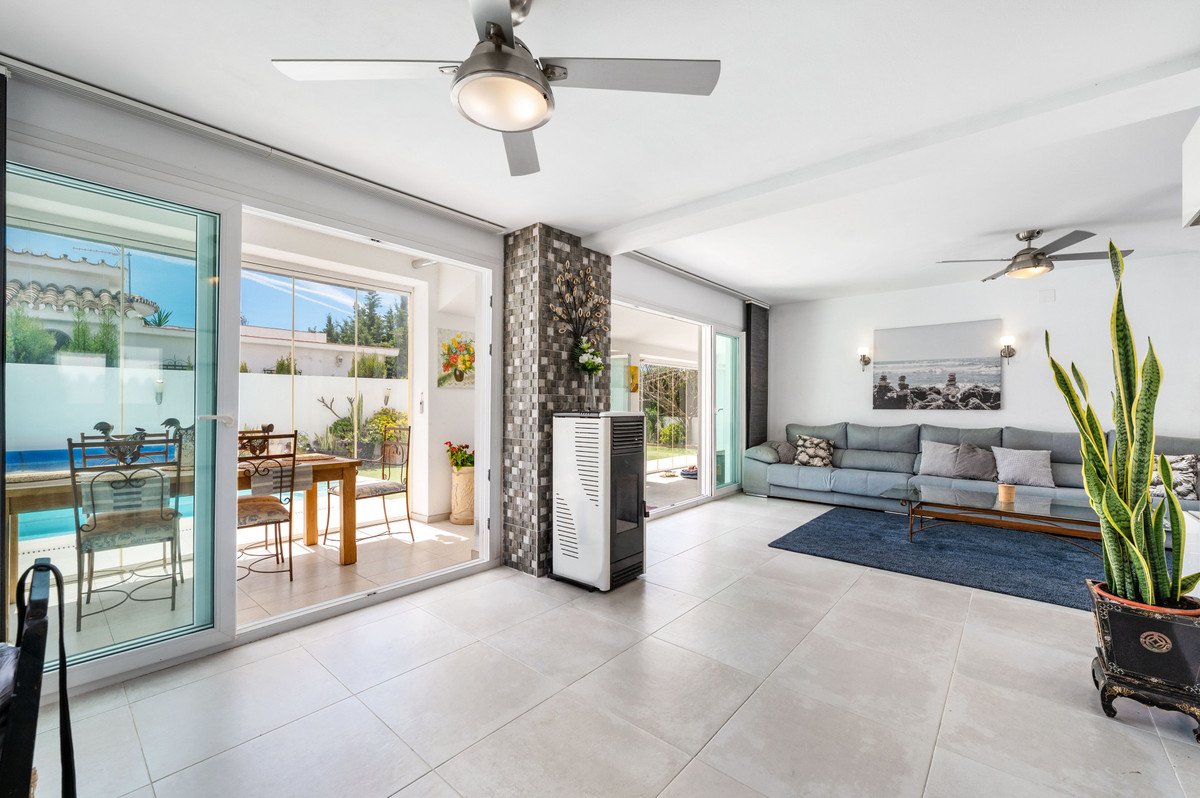 Modern living room with large windows overlooking a swimming pool and garden