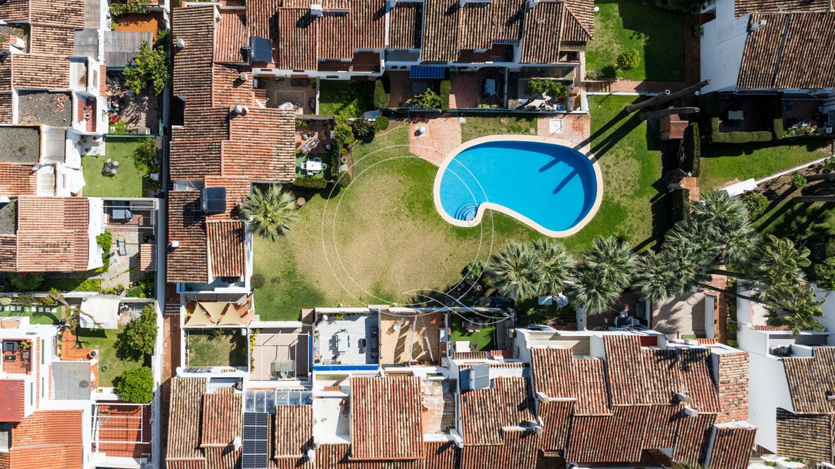 Aerial view of a resort complex with a kidney-shaped pool surrounded by palm trees and townhouses.