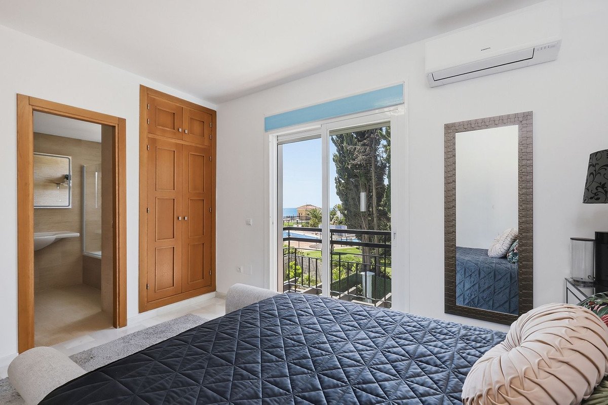 Spacious bedroom with ocean view, balcony, wooden closet, en-suite bathroom, and air conditioning.
