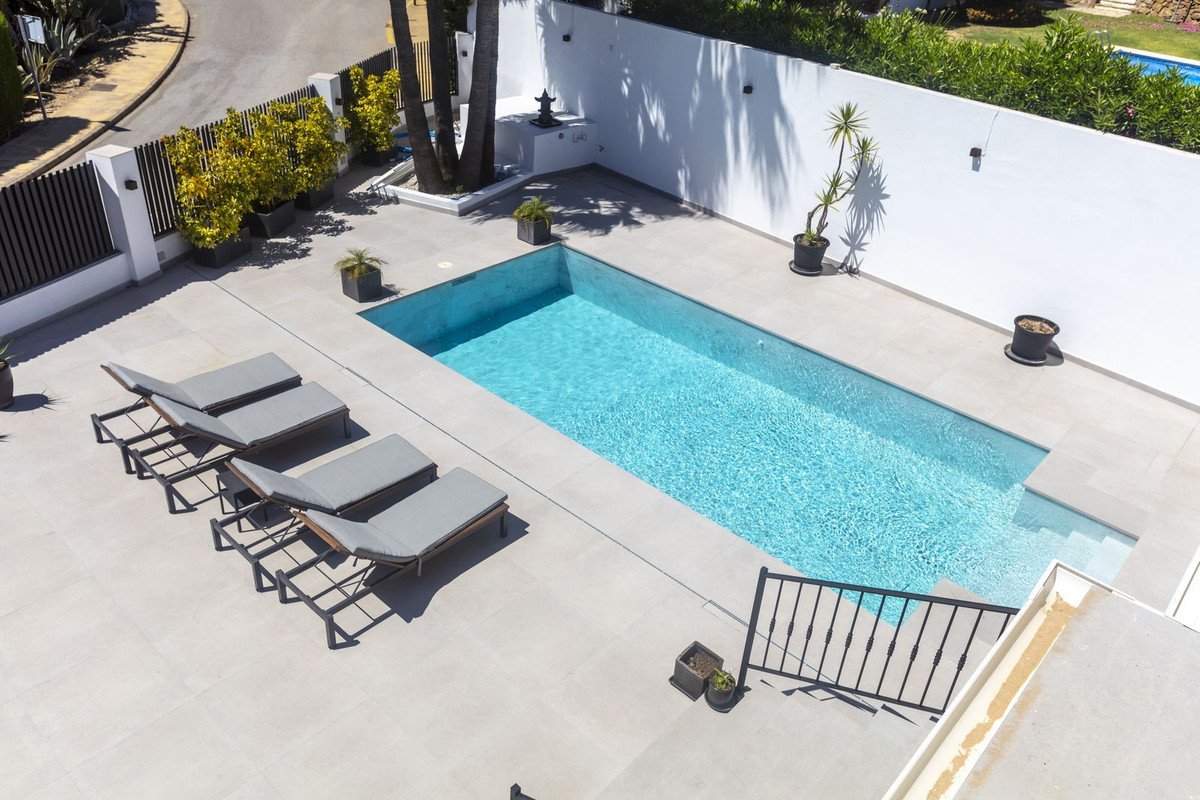 Swimming pool with lounge chairs and potted plants on a sunny terrace