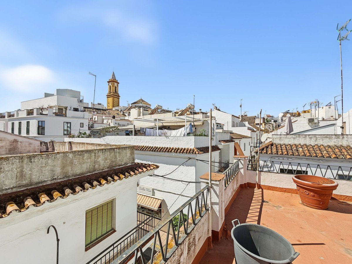 View of rooftops and a bell tower in a Spanish town under a clear blue sky.