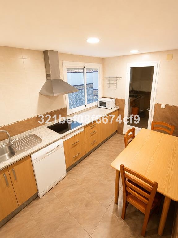 Modern kitchen with wooden cabinets, dining table and chairs, and a window view.