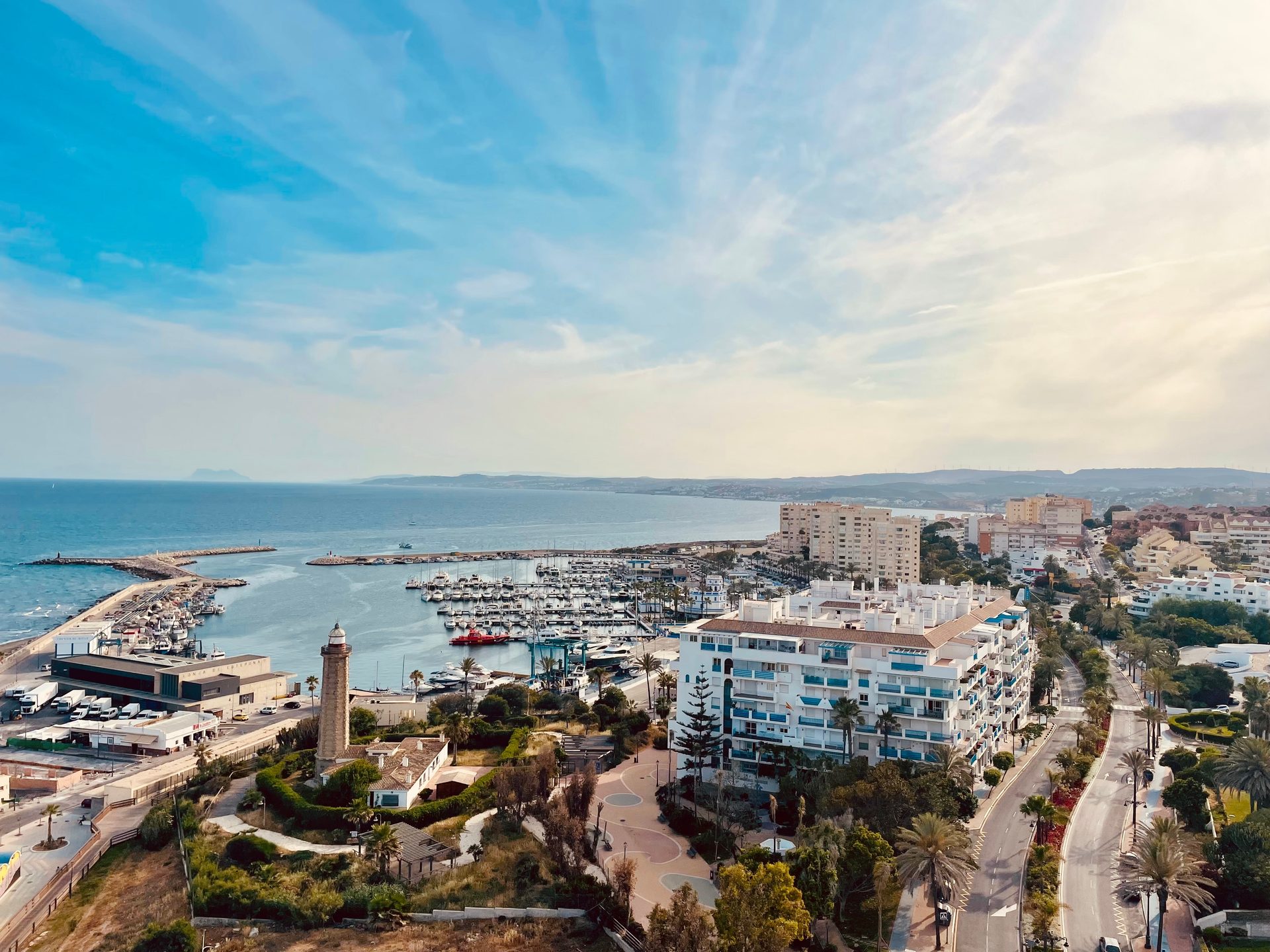Aerial view of a coastal resort with a marina, pool, and sea view.
