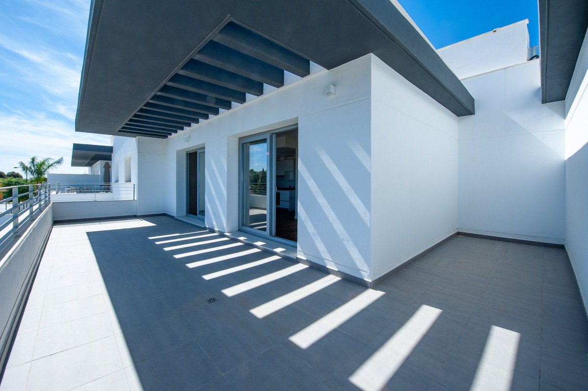 Modern terrace with white walls, grey tiling, and shadow patterns from a slatted roof. Includes sliding glass doors leading inside.
