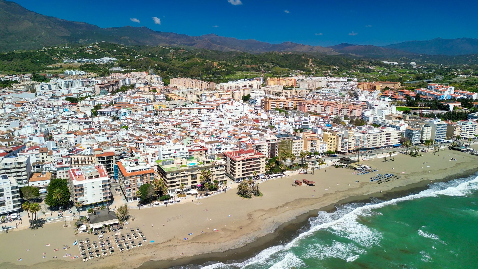 Aerial view of a coastal town with a sandy beach and ocean waves.