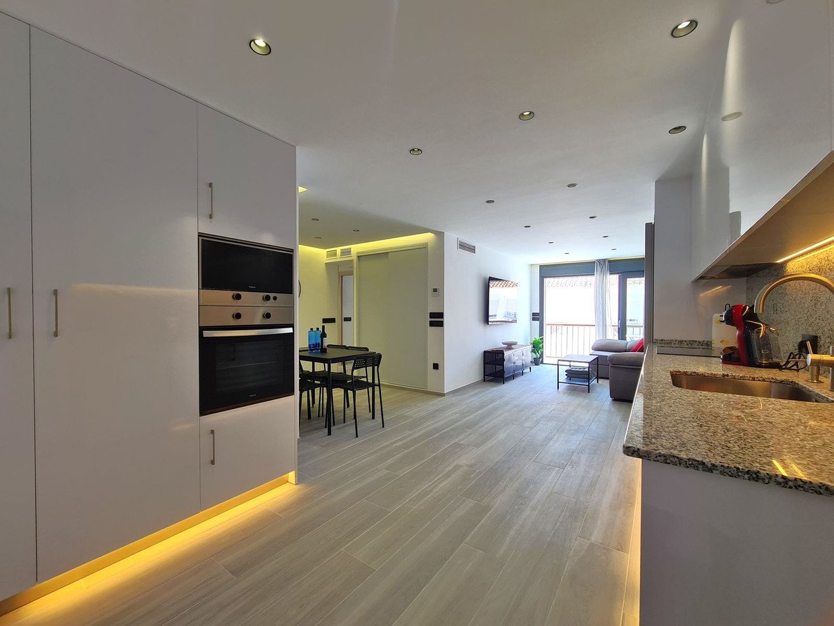 Salón moderno diáfano con cocina, comedor y vista a balcón.