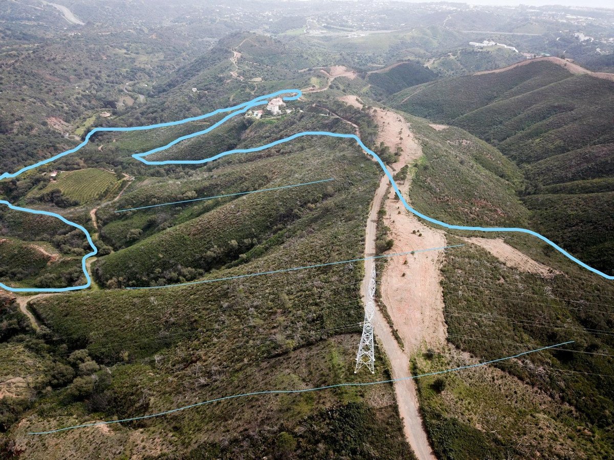 Aerial view of a large estate situated on a hillside with expansive mountain and valley views. Marked with blue lines.