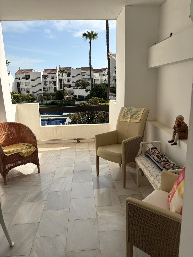 Balcony with seating, tiled floor, and view of pool and apartment buildings