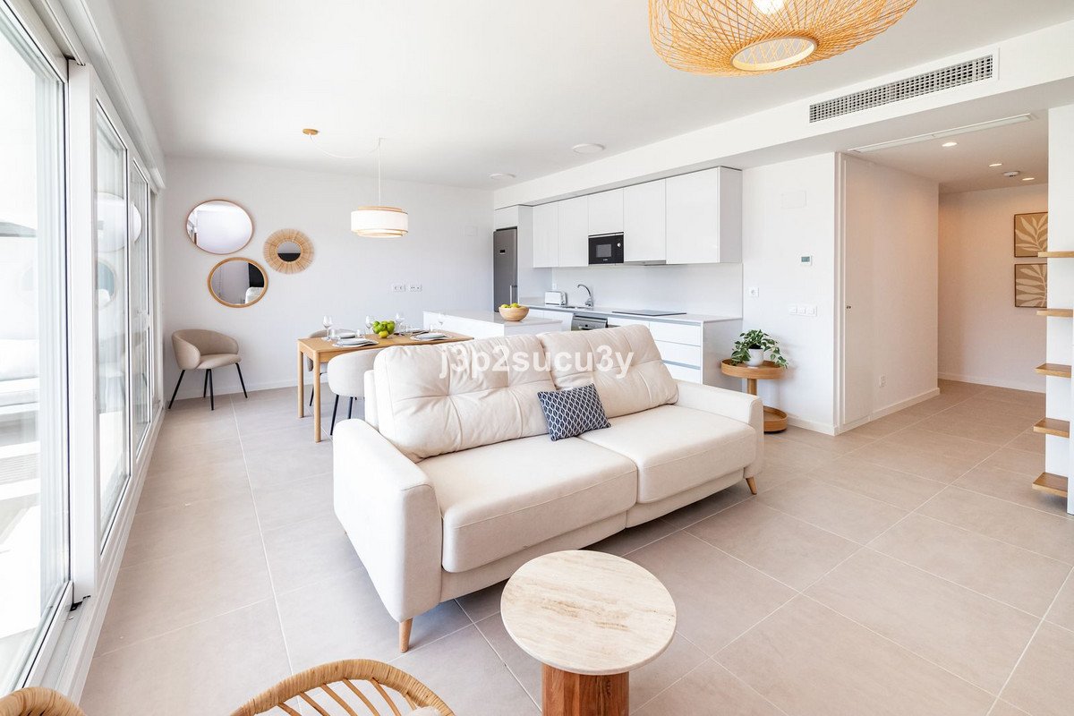 Bright and airy living and dining area with an open-plan modern kitchen, featuring a sofa and dining table.