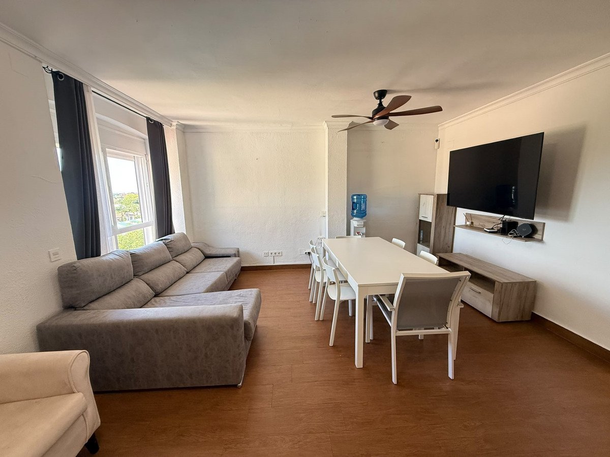 Spacious living and dining area with a large sectional sofa, dining table, chairs, and a wall-mounted TV.