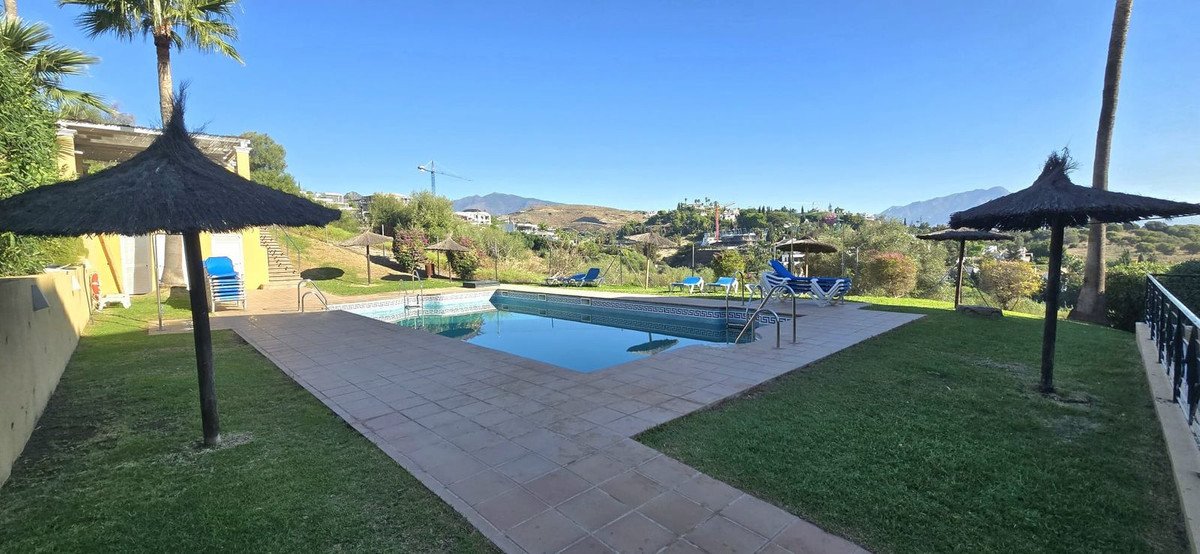 Outdoor swimming pool with mountain view, lounge chairs, and thatched umbrellas