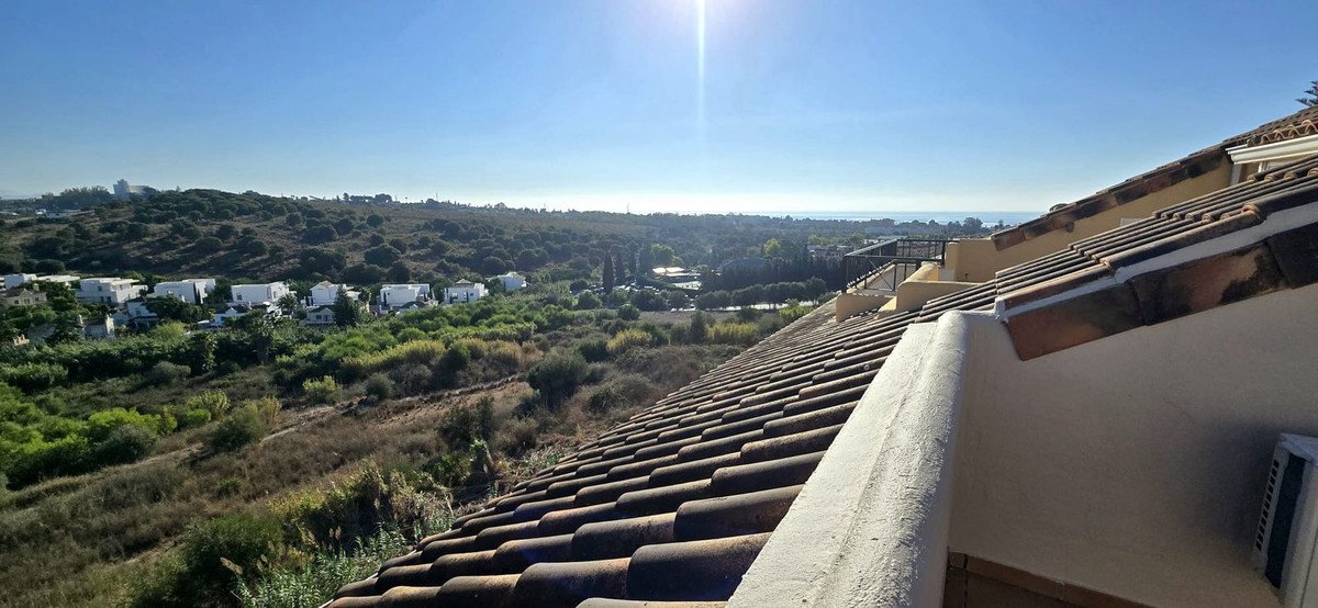Rooftop view of hills, landscape, and distant buildings under bright sun