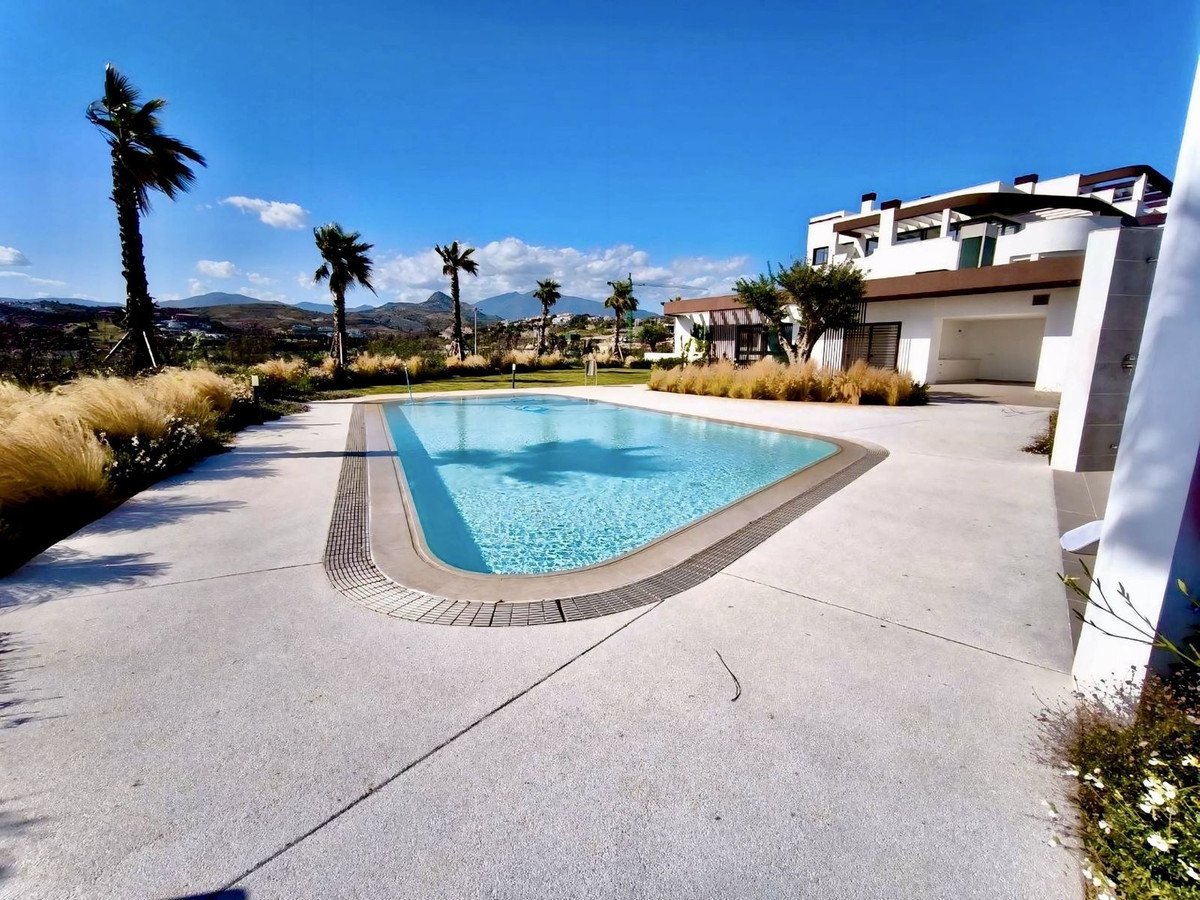 A modern villa with a swimming pool and palm trees, set against a backdrop of hills and a clear blue sky.