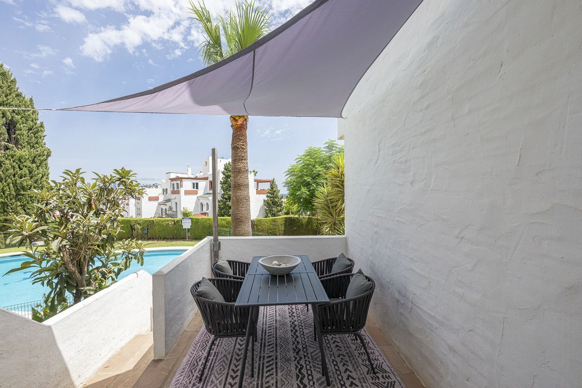 A patio dining set with a pool and palm trees visible in the background, offering a relaxing outdoor space.