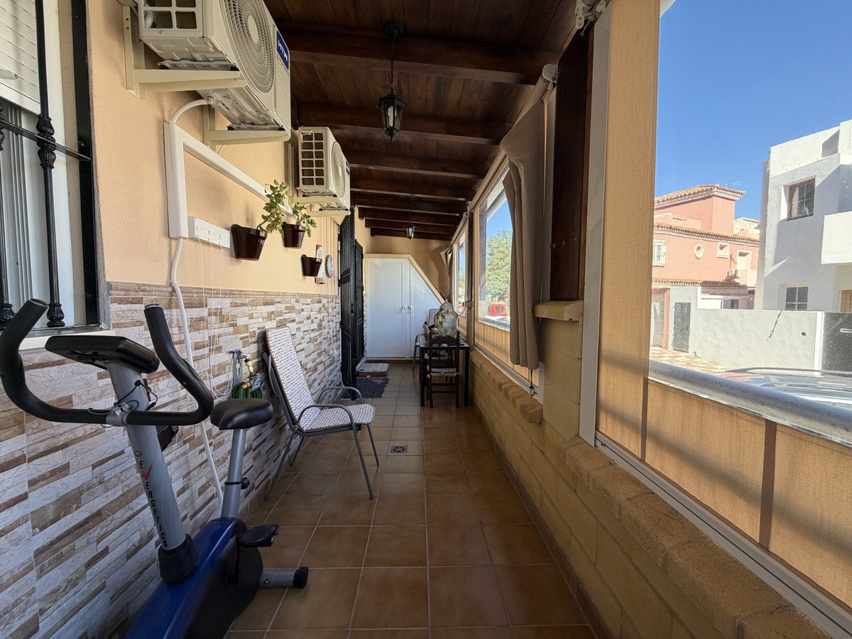 Covered balcony with exercise bike, chairs, and outdoor seating area